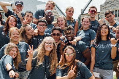 Student members of the Thrive Living-Learning Community in Thrive T-shirts at a group retreat, pictured outside residence halls with Hokie Stone.
