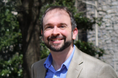 Portrait of Justin Lemkul wearing a suit outside with a tree behind him.