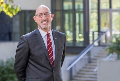 Photo of Daniel Givens, Dean of the Virginia-Maryland College of Veterinary Medicine, posing for a photo outside and smiling.