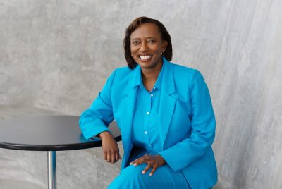 Portrait of Kelly Oaks in a business suit, sitting at a table.