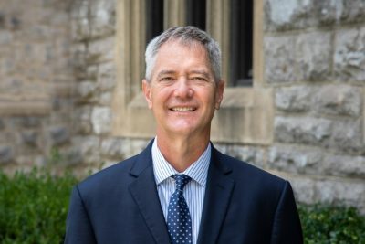 Headshot of Kevin Pitts in a suit outside in front of Hokie Stone.