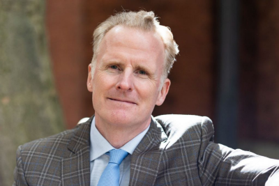 Headshot of Simon Allen wearing a suit. 