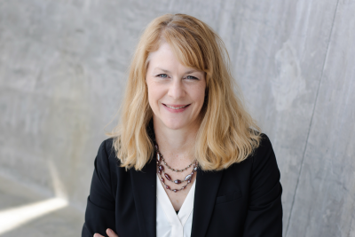 Portrait of Brandy Salmon wearing a suit, smiling with her arms crossed.